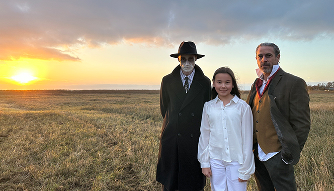 Alma och två andra skådespelare går över ett fält i solnedgången.